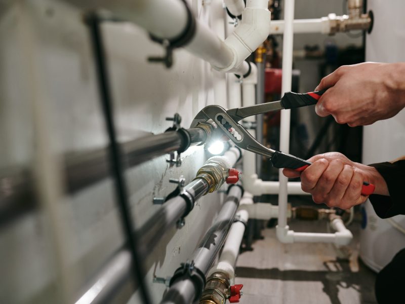 Hands of technician or plumber repairing broken pipes in toilet
